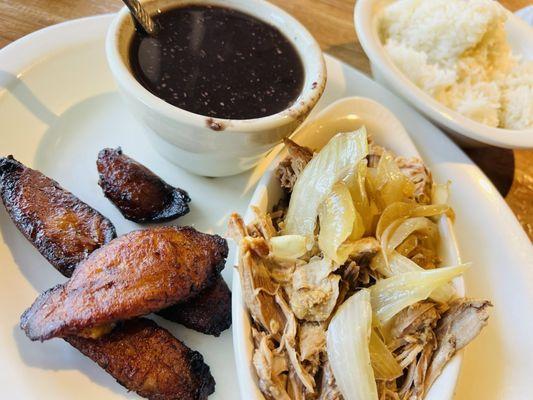 Lechon entree with white rice, black beans, and sweet plantains.