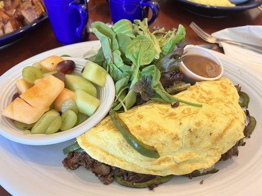 Steak and cheese omelet with greens and fruit