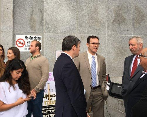 Nic Cocis with lawyers from the defense team conferencing outside the courthouse.