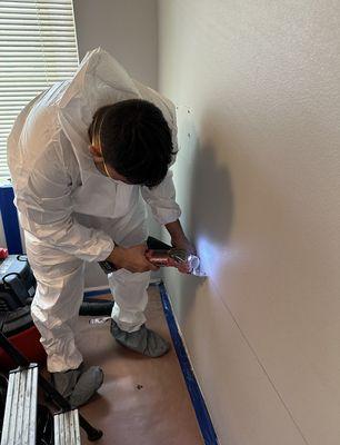 Technician cutting and removing drywall