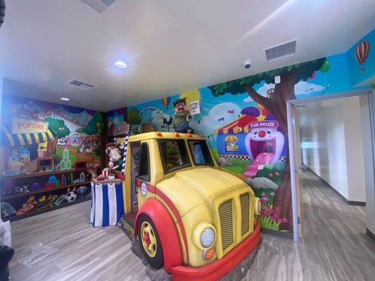 Sweet school bus for kids to play in while they wait. Inside is mini TVs playing Disney or Pixar movies