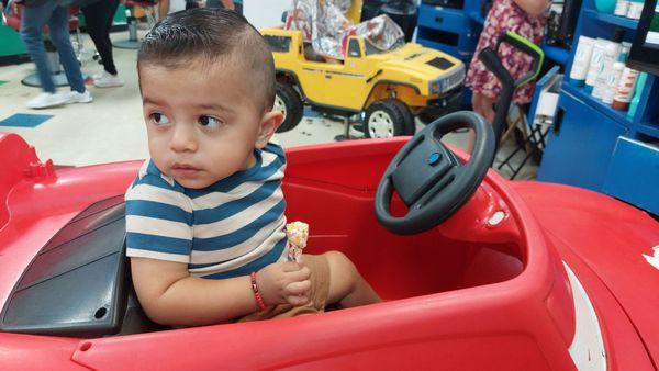 Riding in the hair cut cars with a lollipop provided by stylist