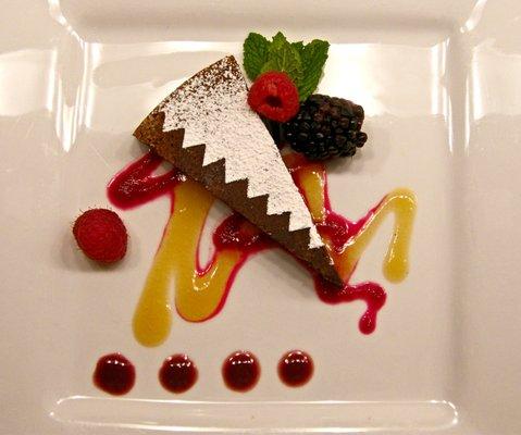 Flourless chocolate pinon torte served with a peach honey sauce, prickly pear syrup, and chokecherry sauce with seasonal fruit.