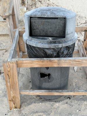 Trash can near the stairs leading from the beach to the upper deck area.