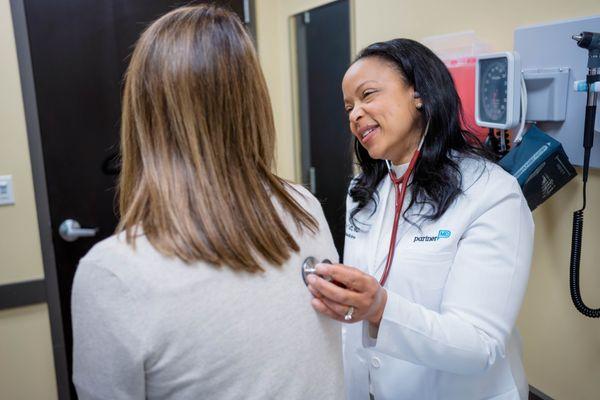 Dr. Tutt listens to a patient with her stethoscope