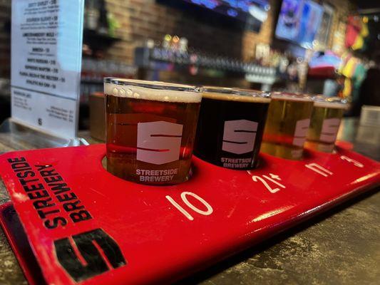 A flight of 4 beers, sitting at the bar