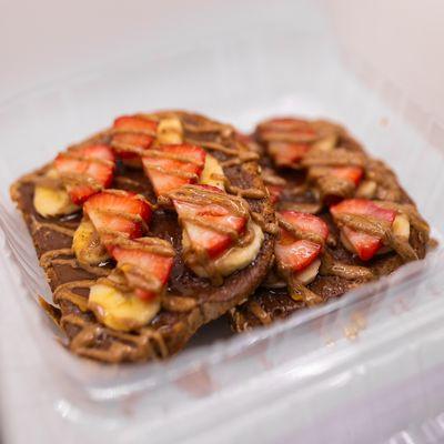 White toast with Nutella spread. Strawberries, bananas, and Nutella drizzle.