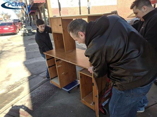 Co-Founder Max Ridenhour guiding the front while Co-Founder Patrick Cymer and his father push a desk to the new location at 209 N Holden St.