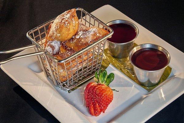 BEIGNETS Fried deliciousness topped with powdered sugar served alongside fresh raspberry and chocolate dipping sauces