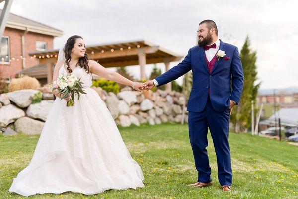 Bride and Groom pose in grassy lawn besides venue