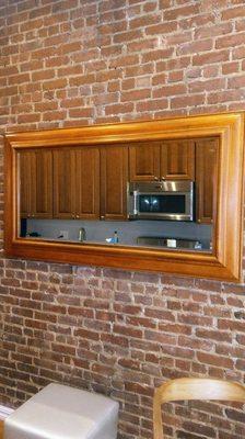 Large mirror mounted onto brick wall