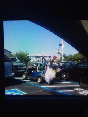 Employee cart clearly parked in a no parking zone making accessible parking inaccessible to a wheelchair user, such as myself.