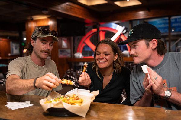 Friends eat cheesy fries at Snowbird's Tram Club