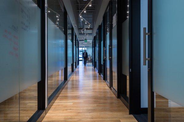 Modern hallways with floor to ceiling glass. Privacy screens make great whiteboards for that next great idea.