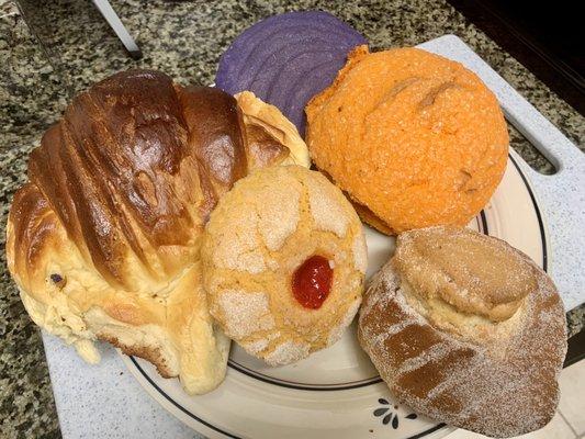 Clockwise from top: Purple concha, orange concha w/sugar crystals, corn bread w/sugar, cookie, giant not-a-croissant but delicious.