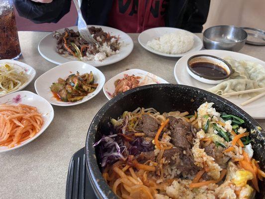 Half eaten hotpot bibimbop, beef bulgogi with the fork, pork mandu off to the right and kimchi veggies to the left.