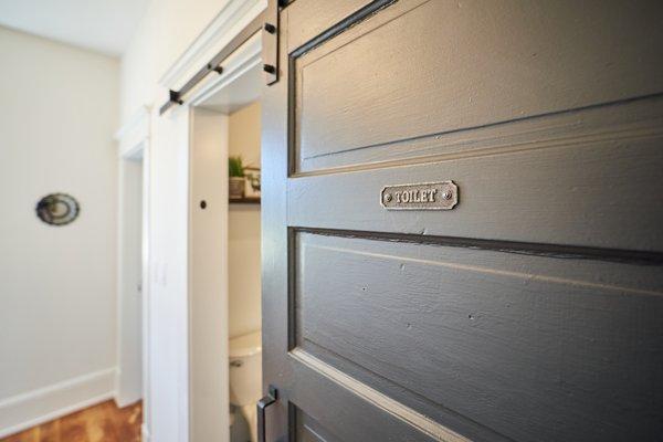 Charming little touches like the TOILET sign on barn door bath.