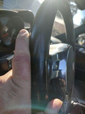 finger for reference on tear on steering wheel.