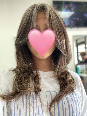 Front of hair including curtain bangs and front layers with peaks of blonde highlights.