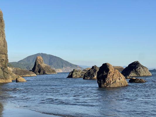 The view of rocks on Port Point Beach, looking south with Humbug Mountain in the background.