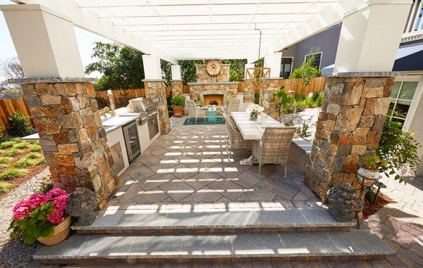 Paver patio with custom outdoor fireplace, kitchen and al fresco dining area.