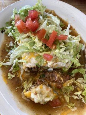 Smothered burrito. In: refried beans, seasoned ground beef, chilies & cheese. Top: choice of red/green sauce, cheese, lettuce & tomatoes.