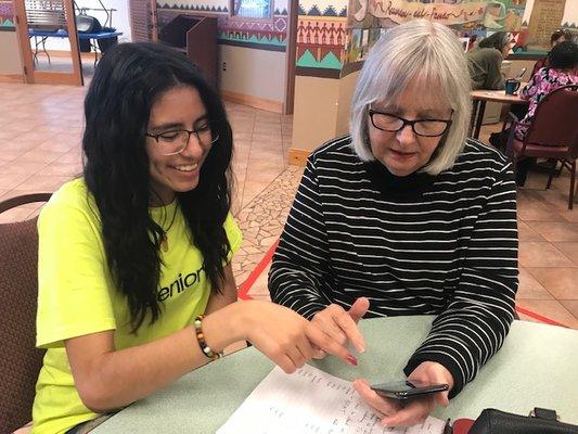 New Teeniors coach tutoring a client on her smartphone.