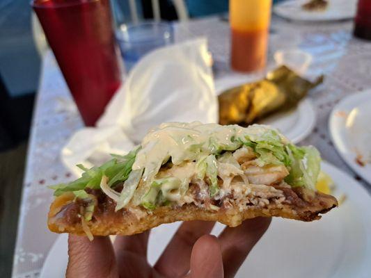 Inside a sope or Enchilada al estilo Salvadoreno. Chicken, black beans, lettuce, tomato, radish, cucumber, cheese. Menu special.