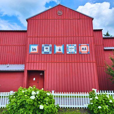 Pictured is a side view of the Red Barn Addition, featuring barn quilts representing key industries in St. Lawrence County.