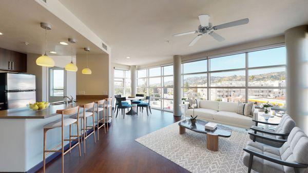 Spacious living and kitchen area featuring hardwood-style flooring and floor-to-ceiling windows.