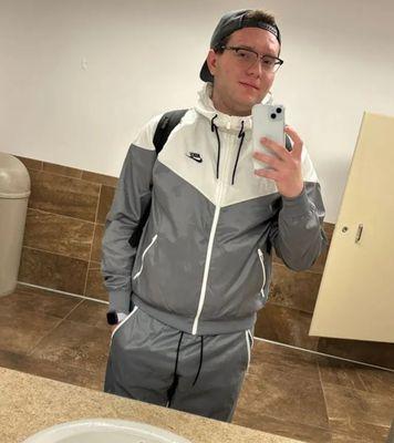 Stefan in a bathroom wearing the gray and white Nike Windrunner jacket and pants