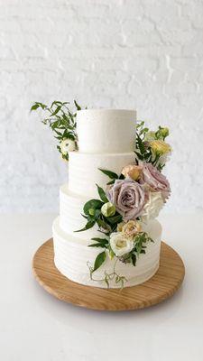 Custom four tier wedding cake with fresh florals giving us all the heart eyes.