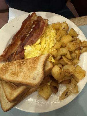 Scrambled eggs, bacon, potatoes and white toast.