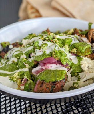 A build-your-own bowl under a thorough blanket of zhoug and garlic dressing.