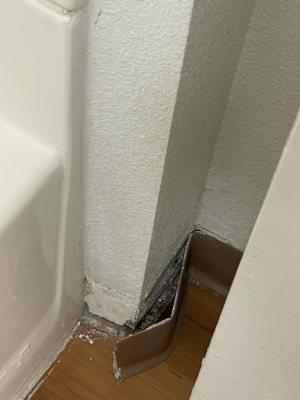 Bathroom baseboard peeling off wall