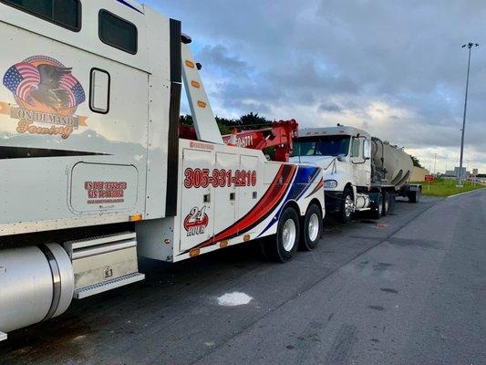 A tow truck towing a truck and trailer combination