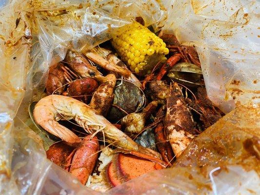 Combo bag with lobster tail, clams, crawfish, shrimp, corn in the cob and potato