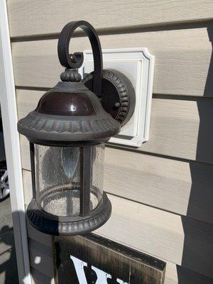 Installation of a wall sconce outside the house on the vinyl siding wall