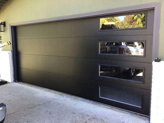 Installed an Flush Panel collection garage door in black color and tinted glass.