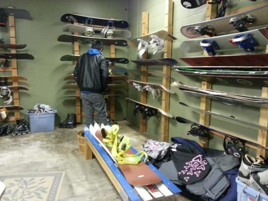 Snowboards, some with bindings already attached. They are located near the backside of the store.