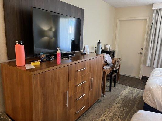 Mini fridge inside the cabinet on far left. Keurig and microwave on table at far right. Door is to balcony