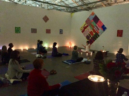 Meditators in the art gallery with candles and colorful art