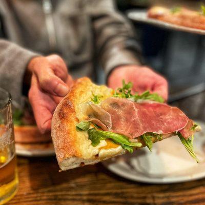 Pizza with lemon béchamel sauce, arugula, fuyu persimmon and prosciutto