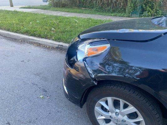 Side view of my car's bumper and headlights completely damaged.