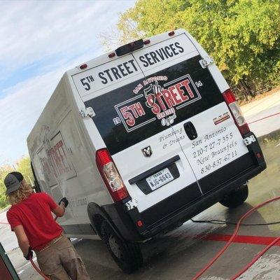 Apprentice washing 5th Street Services plumbing van