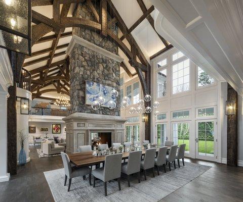 Large great room with wooden beams, a fireplace, and a dining table.