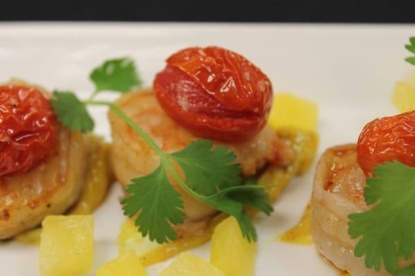 Grilled and glazed shrimp over curry aioli with roasted cherry tomatoes, compressed pineapple and cilantro sprigs