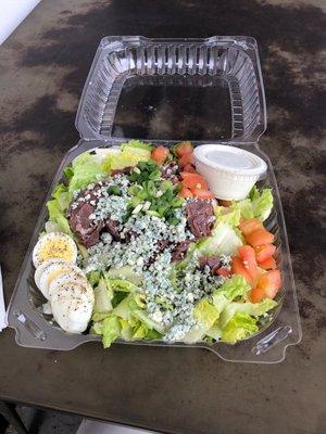 The Deep Blue Salad with romaine, blue cheese, tomato , , steak, green onion, and blue cheese dressing.