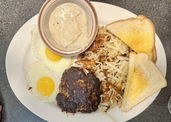 Sausage Patty, sunny-side up eggs, toast, and hash browns, with a side of gravy.