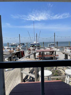 view of outside deck seating with boat dock area. they also have umbrellas for the tables.